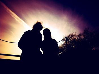 Low angle view of silhouette people standing against clear sky