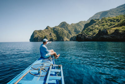 Men on boat in sea against clear sky