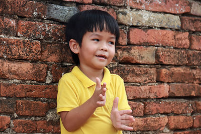 Portrait of boy smiling against brick wall