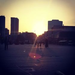 Silhouette of people in city at sunset