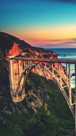 Bridge over river against sky during sunset