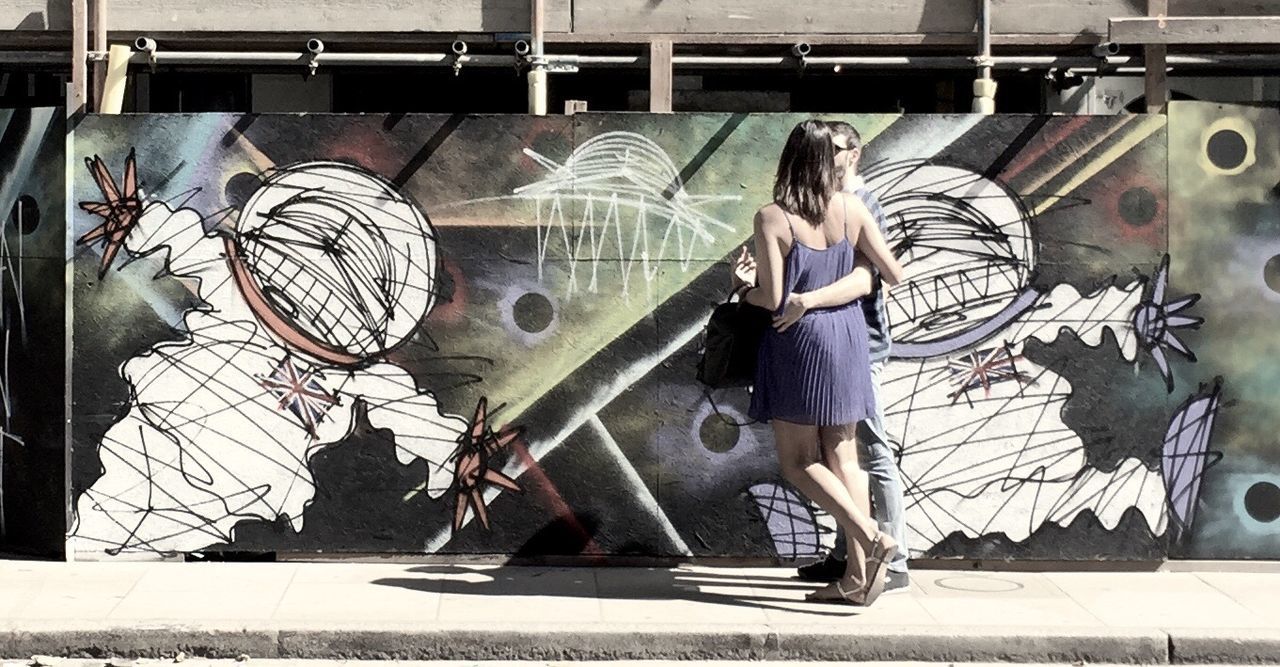 FULL LENGTH OF WOMAN STANDING ON GRAFFITI