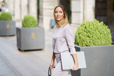 Portrait of young woman standing against building