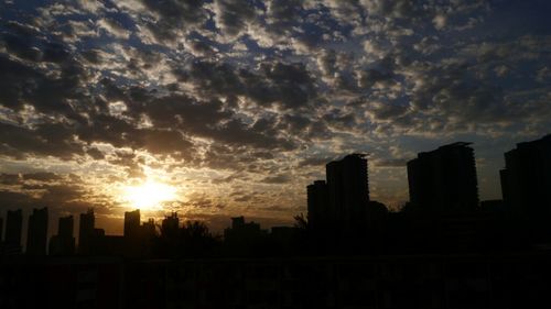 Cityscape against cloudy sky at sunset