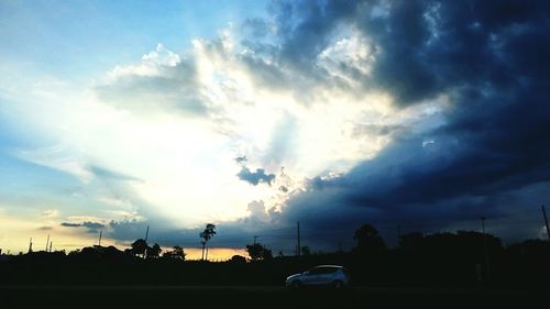 Silhouette of trees against cloudy sky