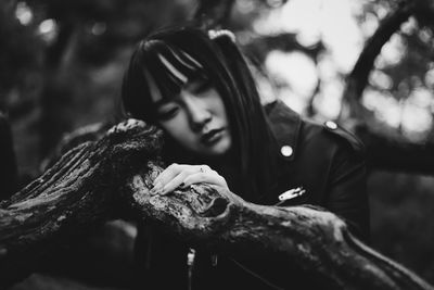 Portrait of young woman looking at tree