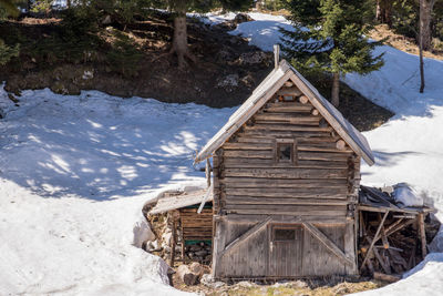 Log cabin by snowcapped mountains during winter