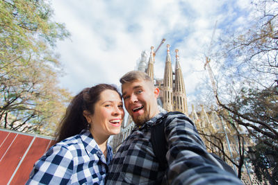 Portrait of smiling young couple against sky