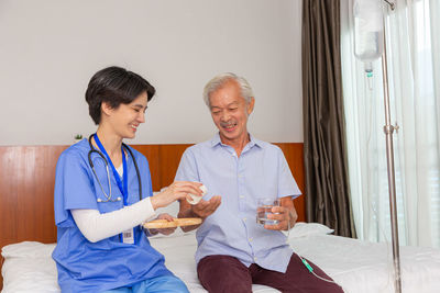 Portrait of smiling female doctor standing against wall