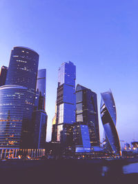 Low angle view of illuminated buildings against clear blue sky