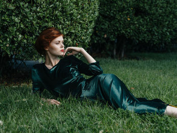 Young woman looking away while lying on lawn