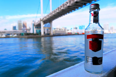 Close-up of water bottle by sea against sky