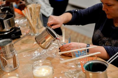Midsection of woman pouring drink in glass on table