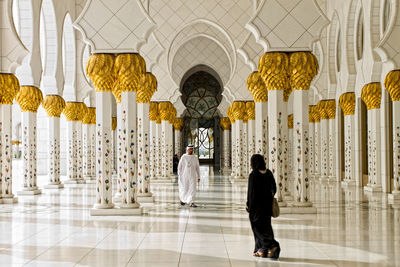 Rear view of people walking in corridor of building