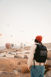 Rear view of man standing on landscape against clear sky