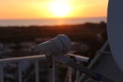 Close-up of metal railing against sky during sunset