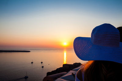 Rear view of woman looking at sea against sky during sunset