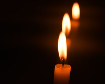 Close-up of lit candle against black background