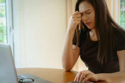 Young woman using mobile phone while sitting on table