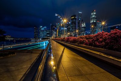 Illuminated light trails on road in city against sky at night