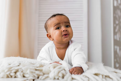 Portrait of cute baby boy on bed at home