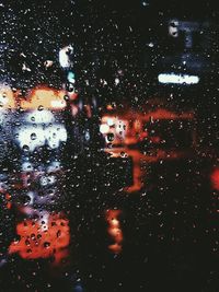 Close-up of wet glass window against sky