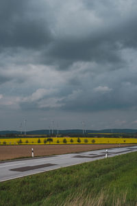 Road amidst field against sky