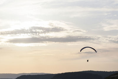 Person paragliding against sky during sunset