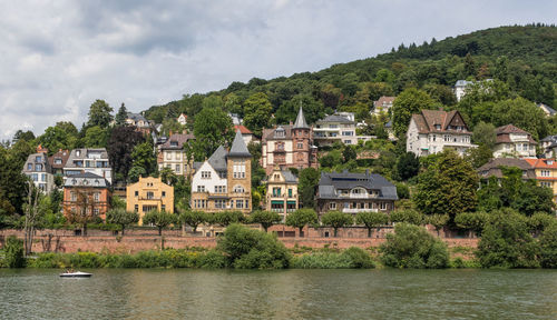 Houses by river in town against sky