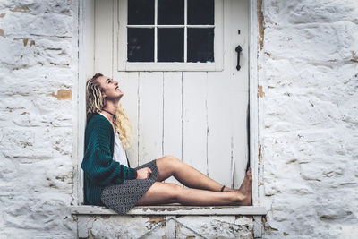 Portrait of young woman sitting on window
