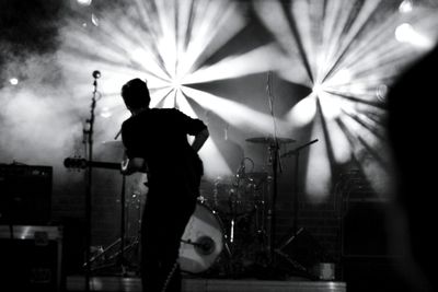 Rear view of man playing guitar at concert