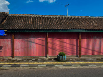 Red shophouse on the street with buildings against the blue sky