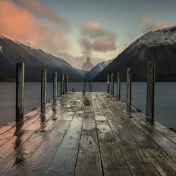 Wooden pier on sea against cloudy sky