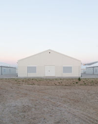 Barn on beach against clear sky