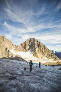 Rear view of people walking on mountain against sky