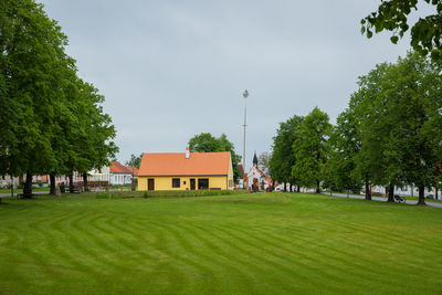 Trees and houses on field against sky