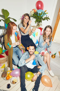 High angle view of smiling friends playing with eyeglasses props at dinner party