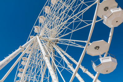 Low angle view of ferris wheel against blue sky