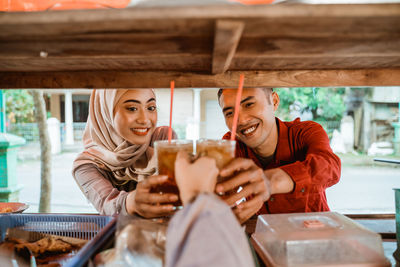 Smiling couple holding smoothie at food stall
