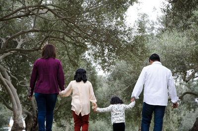 Rear view of people walking along plants