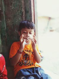 Boy blowing bubble while sitting at home