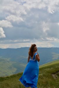 Rear view of woman standing on landscape against sky