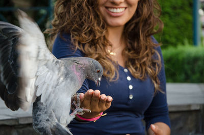 Midsection of woman holding bird against blurred background