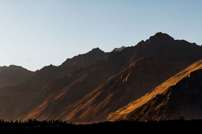 Scenic view of silhouette mountains against clear sky during sunset