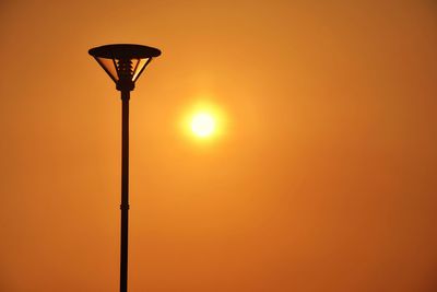 Low angle view of street light against clear orange sky