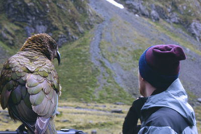 Side view of man standing by kea bird