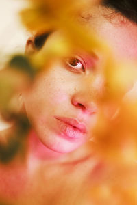 Young gentle woman with brown eyes and curly hair on pure skin looking at camera