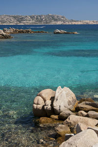 Rocks on sea shore against blue sky