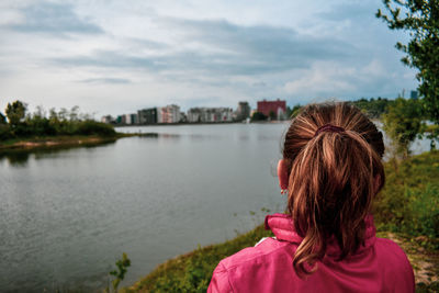 Rear view of girl looking at lake in city