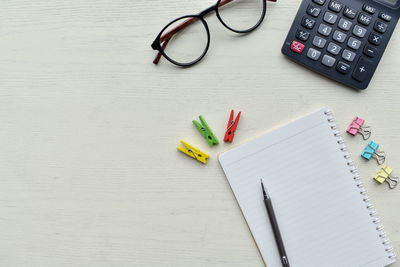 High angle view of book and eyeglasses with calculator on table